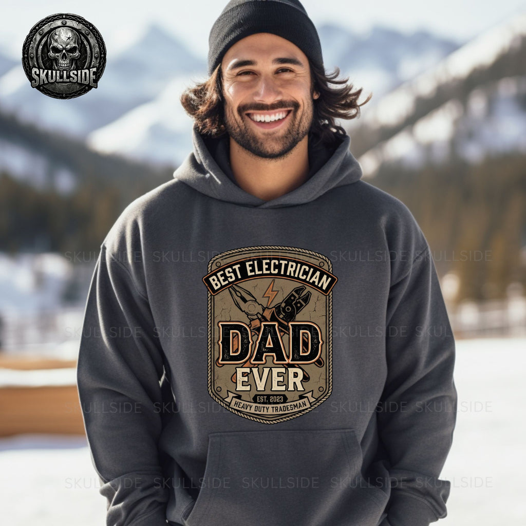 Man wearing a hoodie with 'Best Electrician Dad Ever' design in a snowy landscape.